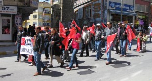 1 Mayıs yürüyüşünde pankart ve kırmızı bayraklarla yürüyen insanlar