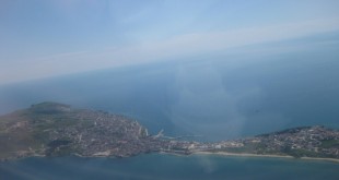 Uçak penceresinden görünen deniz kıyısı ve yarımadadaki şehir