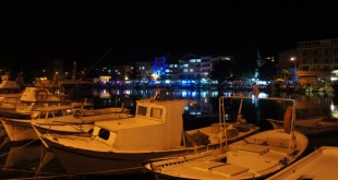 Gece limanda yan yana bağlı sarı ışıkla aydınlanmış balıkçı tekneleri