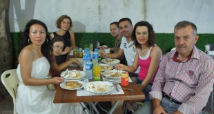 Yemek masasında tabaklar önünde gülümseyen misafirler