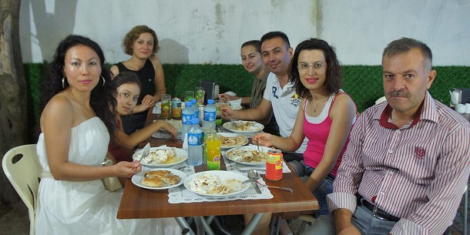 Yemek masasında tabaklar önünde gülümseyen misafirler