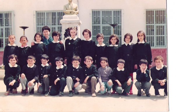 Siyah önlüklü öğrencilerin büst önünde çekilmiş eski sınıf fotoğrafı