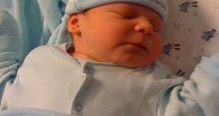 Mavi kıyafetli ve bereli uyuyan yeni doğmuş bebek