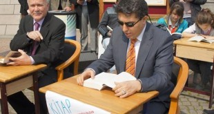 Okul sırasında oturup kitap okuyan iki takım elbiseli erkek