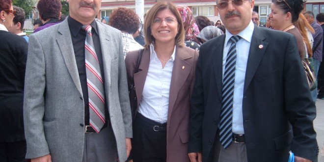 Etkinlik alanında ceketli iki erkek ve ortada bir kadın poz veriyor