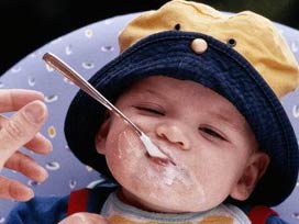 Şapkalı bebek kaşıkla mama yiyor