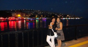 Gece deniz kıyısında ışıklı koyun önünde poz veren iki kadın