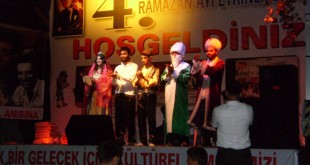 Ramazan etkinliği sahnesinde kostümlü oyuncular ve arkadaki pankart