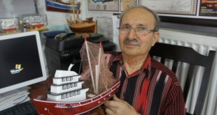 Elinde balıkçı teknesi maketi tutan yaşlı usta