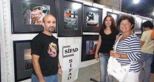 SİFAD sergisinde panolara asılı fotoğrafların önünde duran üç kişi