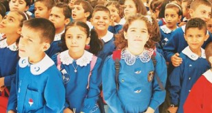 Mavi önlüklü ilkokul öğrencileri sıralar halinde bekliyor