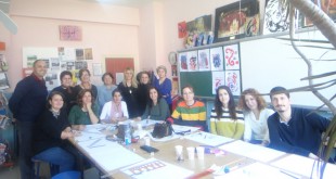 Sınıfta masa çevresinde toplanıp çizim yapan kadın ve erkek grup