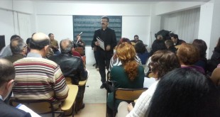 Sınıfta yeşil tahta önünde ayakta konuşan eğitmen ve dinleyiciler