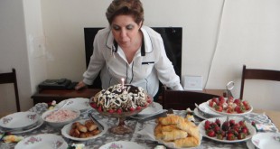 Zengin sofrada doğum günü pastasındaki mumu üfleyen kadın
