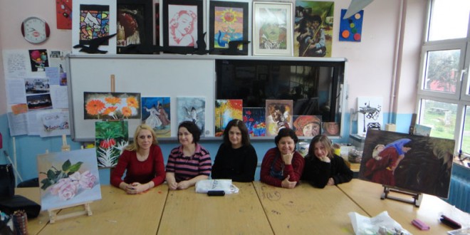 Sanat atölyesinde masa başında oturan kadınlar ve arkadaki tuvaller