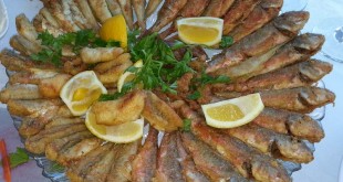Büyük tabakta limon dilimleri ve maydanozla servis edilen kızarmış balıklar
