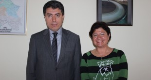 Takım elbiseli erkek ile yeşil çizgili kazaklı kadın yan yana poz veriyor