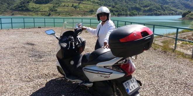 Baraj gölü kıyısında motosikletinin yanında duran kadın
