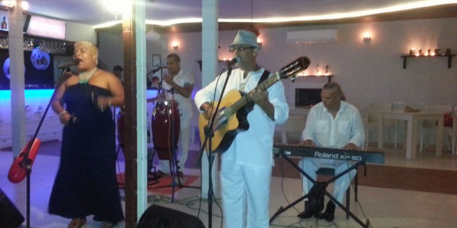 Sahnede şarkı söyleyen kadın, gitarist ve klavye çalan erkek