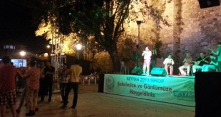 Tarihi surların önündeki sahnede gece konseri ve dans eden insanlar