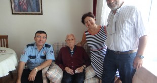 Koltukta oturan yaşlı adam ile yanındaki polis, kadın ve erkek