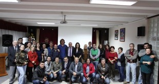 Toplantı salonunda ayakta ve oturarak toplu hatıra çekilen kalabalık grup