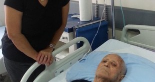 Hastane odasında yatakta yatan yaşlı erkek ve yanındaki kadın