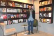 Kitap kafede raflar önünde duran bir erkek