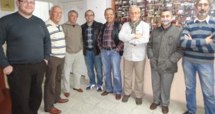 Koridorda fotoğraf duvarının önünde poz veren bir grup erkek