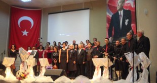 Sahnede Türk bayrağı ve Atatürk portresi önünde konser veren koro