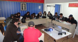 Kurs salonunda masa etrafında oturup not alan katılımcılar