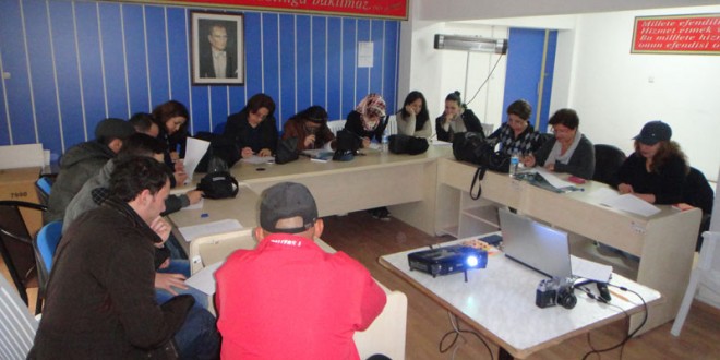 Kurs salonunda masa etrafında oturup not alan katılımcılar