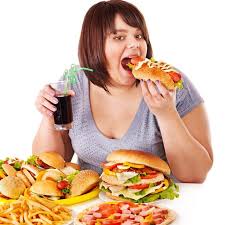 Hamburger yiyip kola içen kadının önünde fast food dolu tabaklar