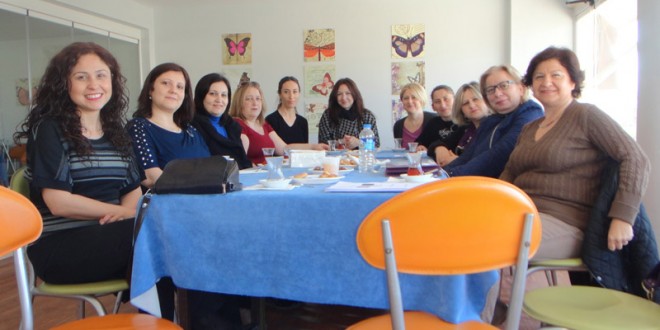 Kurs salonunda mavi örtülü masa etrafında oturan kadınlar