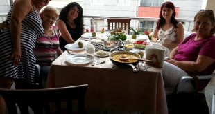 Balkondaki kahvaltı masasında oturan gülümseyen kadınlar