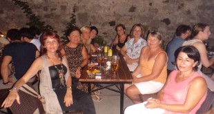 Gece taş duvar önünde masada oturan bir grup