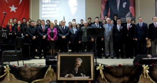 Sahnede Atatürk portresi önünde duran koro görülüyor