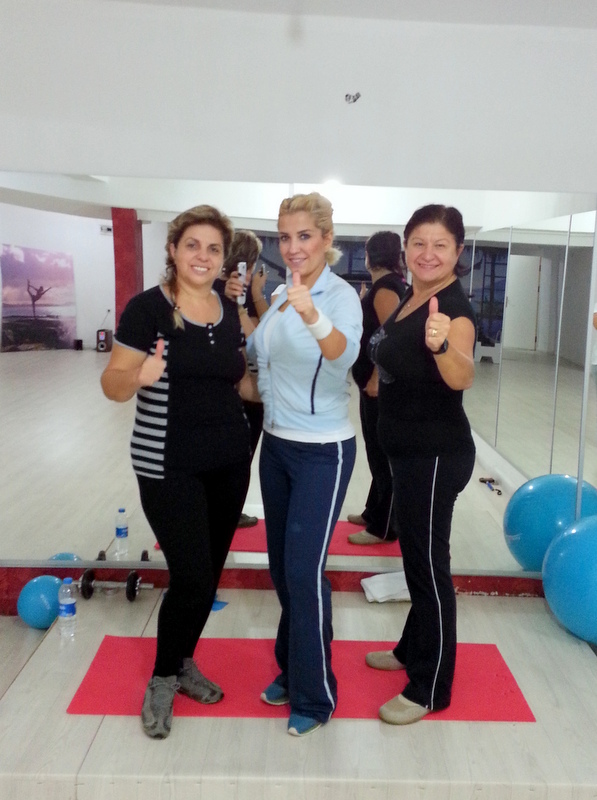 Spor salonunda poz veren üç kadın görülüyor