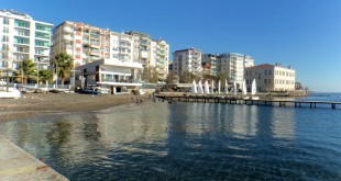 Sahildeki binalar ve durgun deniz manzarası görülüyor