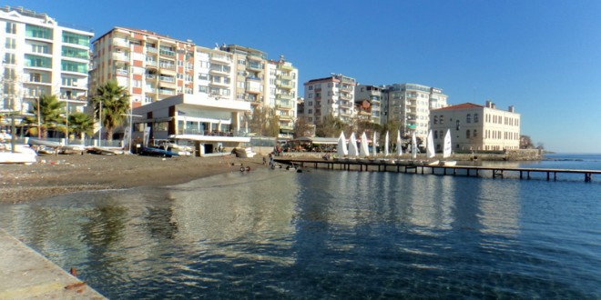 Sahildeki binalar ve durgun deniz manzarası görülüyor