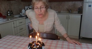 Doğum gününde mum üfleyen bir kadın mutfak masasında