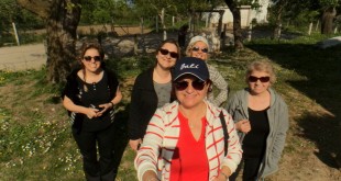 Köy girişinde taş duvar önünde kadınlar grubu selfie çekiyor