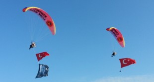 Gökyüzünde bayraklarla inen iki yamaç paraşütçüsü