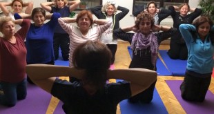 Nefes yogası dersinde matlar üzerinde diz çöken grup.