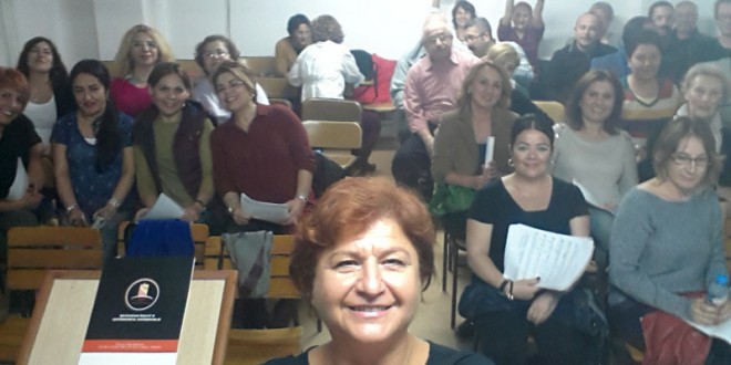 Elinde nota defteriyle oturan kalabalık dinleyici grubu.
