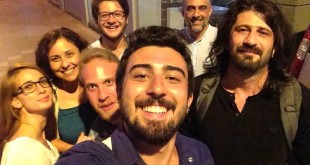 İç mekanda kalabalık bir grup gülümseyerek selfi çekiyor