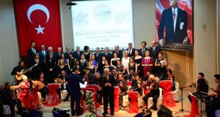 Kırmızı sahnede koro ve orkestranın toplu görünümü