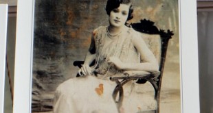 Sergilenen eski bir fotoğrafta koltukta oturan genç bir kız