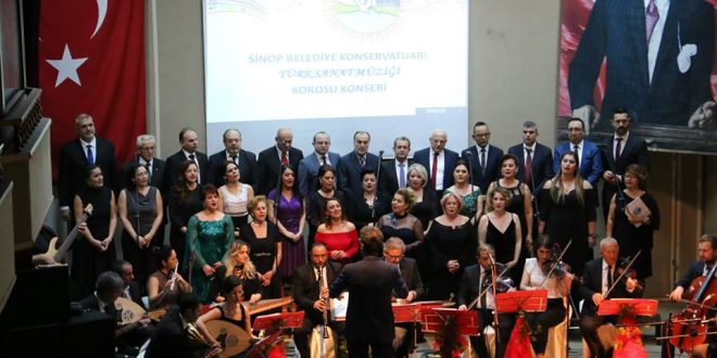 Türk bayrağı eşliğinde sahnede performans sergileyen koro ve orkestra