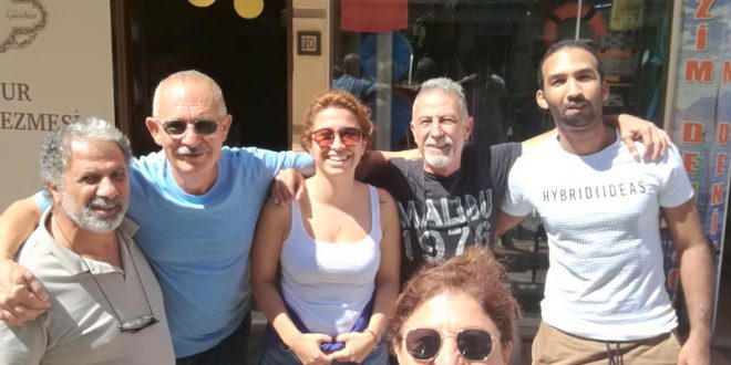 Türk bayraklı bir dükkan önünde poz veren beş kişilik grup